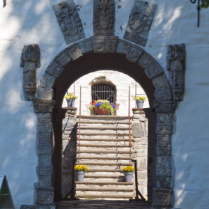 Ørland, Austrått Manor, looking through at gate in a stone wall, inside there is a staircase of stone, flowers on the stairs and on the top.