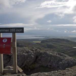 The Mountain of Rusaset, a sign on a peak, the sun shines on dark clouds, sea in the background