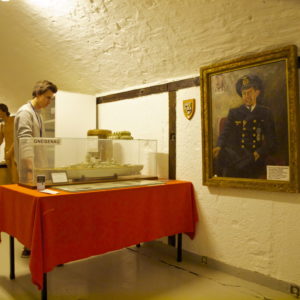 Austrått fort, Ørland, Austrått agrotourism, a young man study the model of a battleship in a museum, painting on the wall to the right