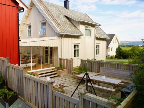 Ørland, Austrått agrotourism, in the foreground an outer dining place with tables and benches, connected to a white house
